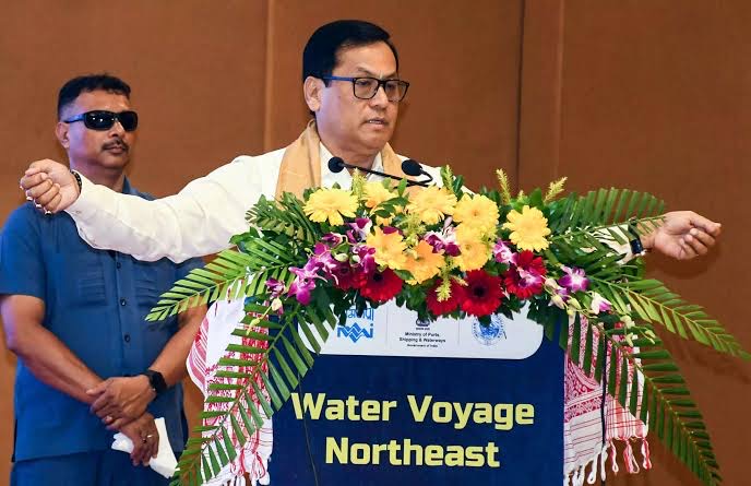 Sarbananda Sonowal speaks at a podium marked 'Water Voyage Northeast' with the logos of the ministry and the Inland Waterways Authority of India