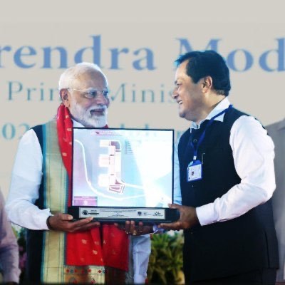 Sarbananda Sonowal and Prime Minister Narendra Modi hold a framed memento together on a stage