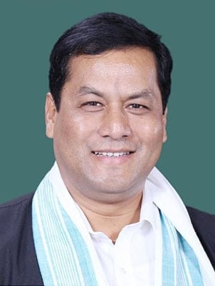 Official member portrait of Sarbananda Sonowal against a teal background, wearing a white shirt and a white gamosa