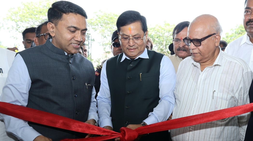Sarbananda Sonowal cuts a red ribbon at an inauguration, flanked by two other dignitaries